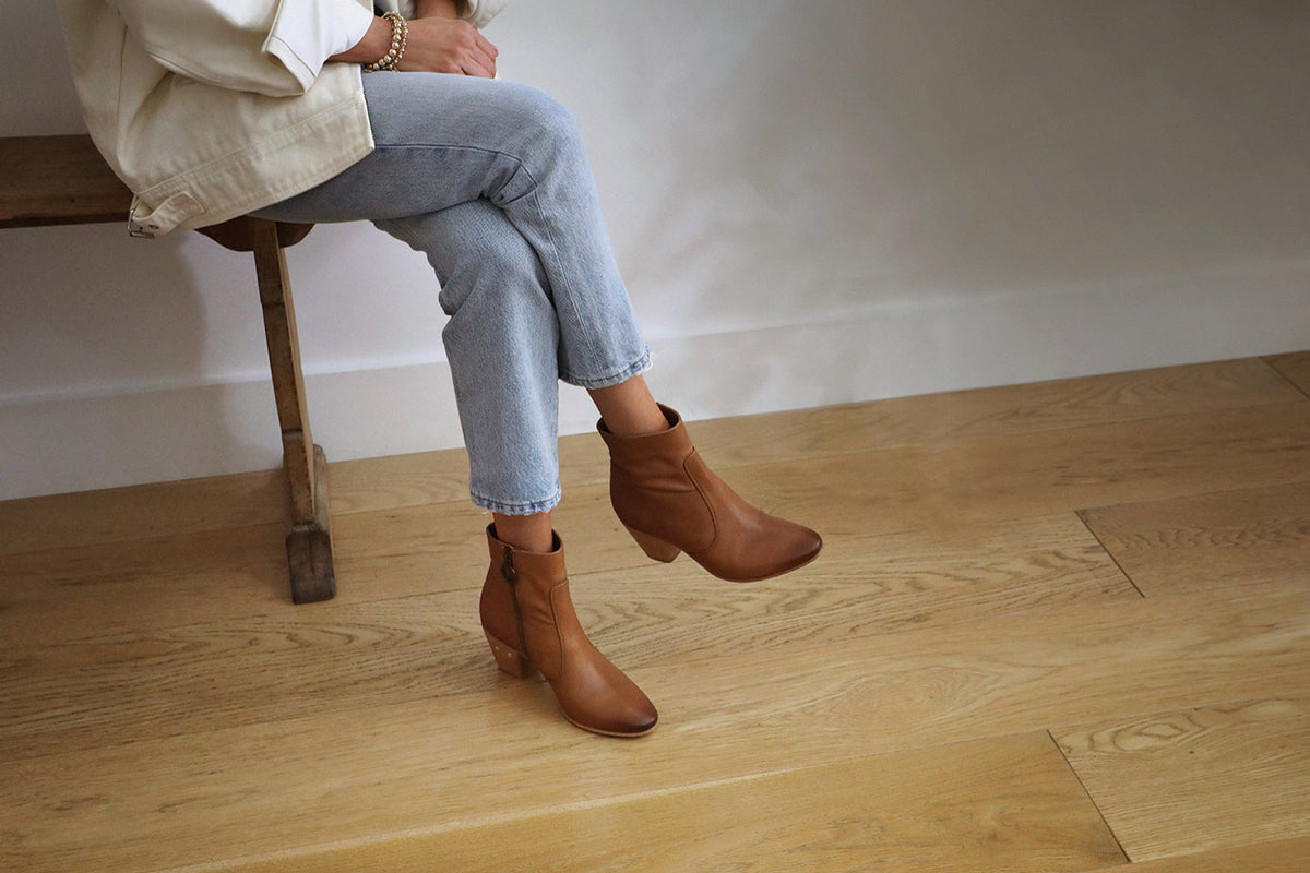 Woman wearing Catbird leather boots in tan with jeans and cream jacket