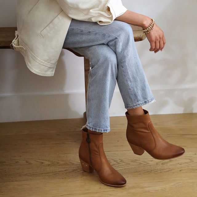Woman wearing Catbird leather boots in tan with jeans and cream jacket