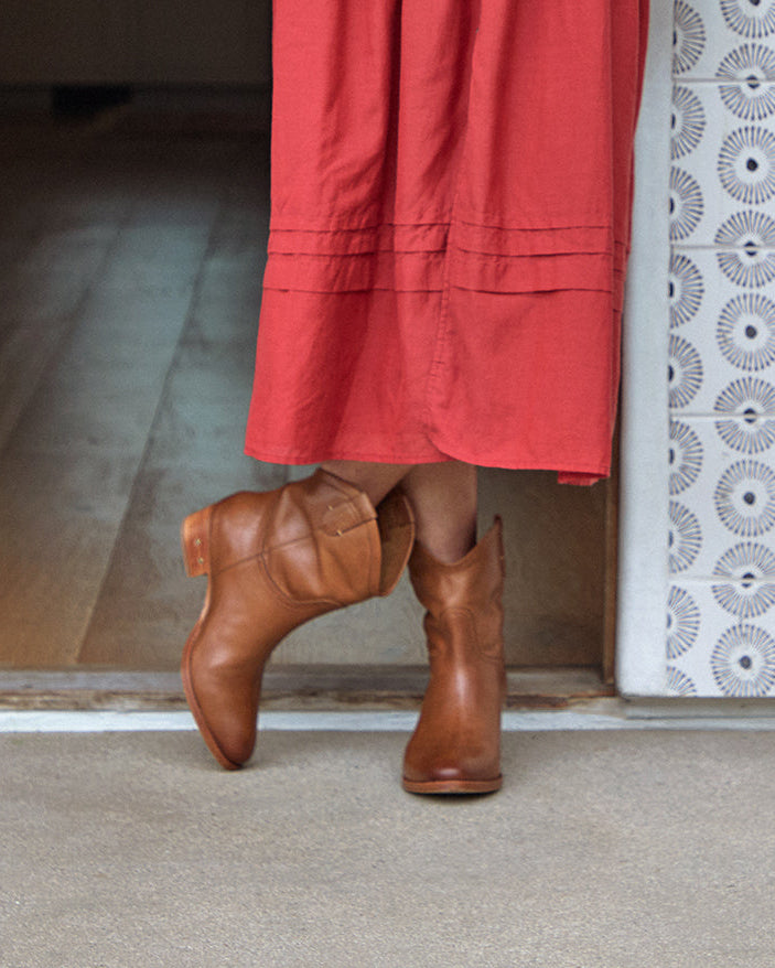 Woman wearing Condor leather boots in tan with red dress standing in doorway