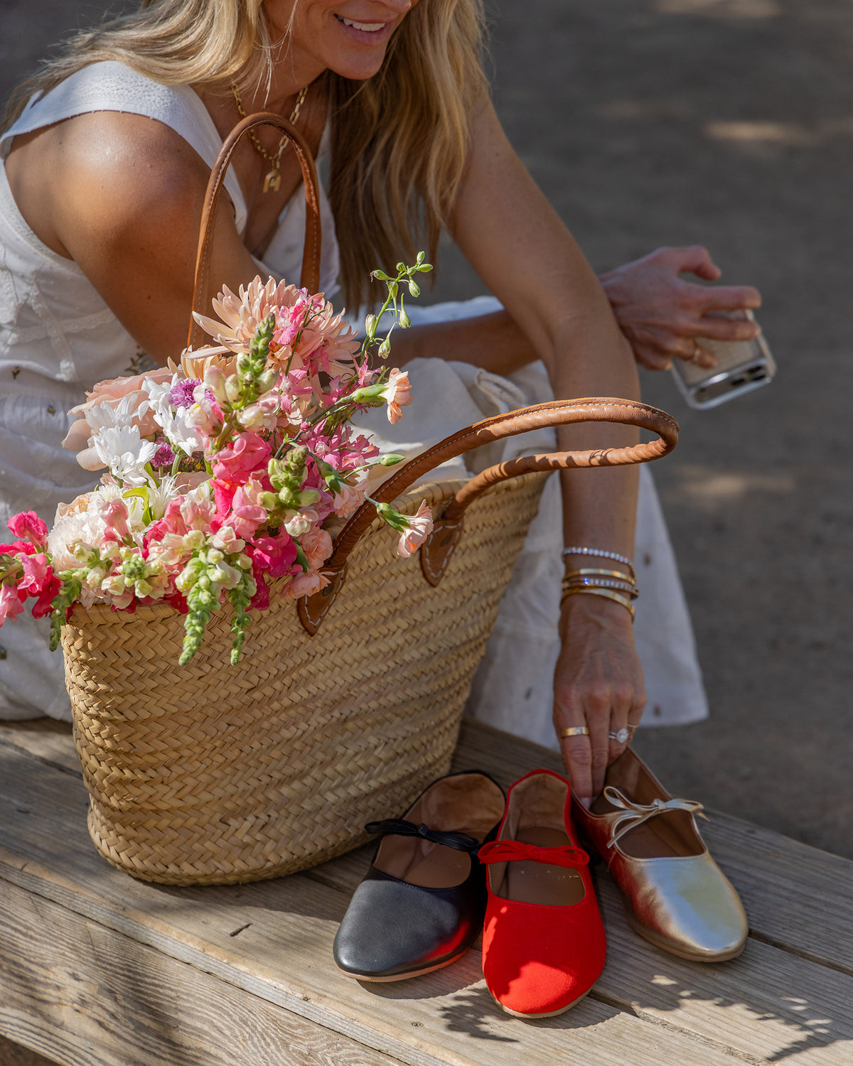 Abbie Crane holding Crane Bow leather mary jane shoes in gold with poppy and black