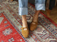 Woman wearing Crane suede mary jane shoe in caramel with jeans on rug