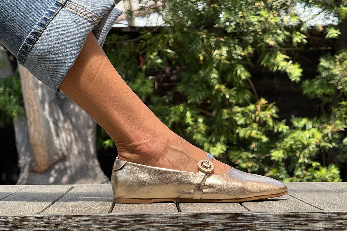 Woman wearing Crane leather mary jane shoes in gold with jeans.
