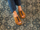 Woman wearing Crest suede slide sandals in caramel with navy stripe with dark jeans