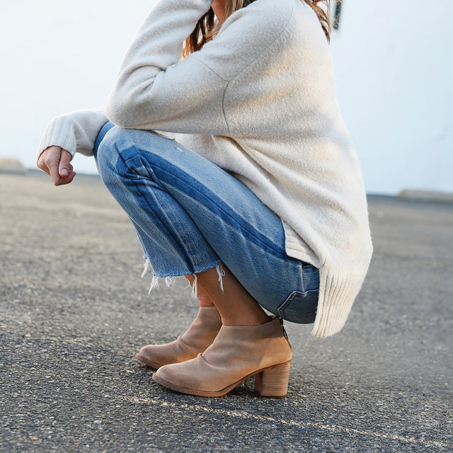 Woman wearing Eaglet suede booties in stone with jeans and sweater._
