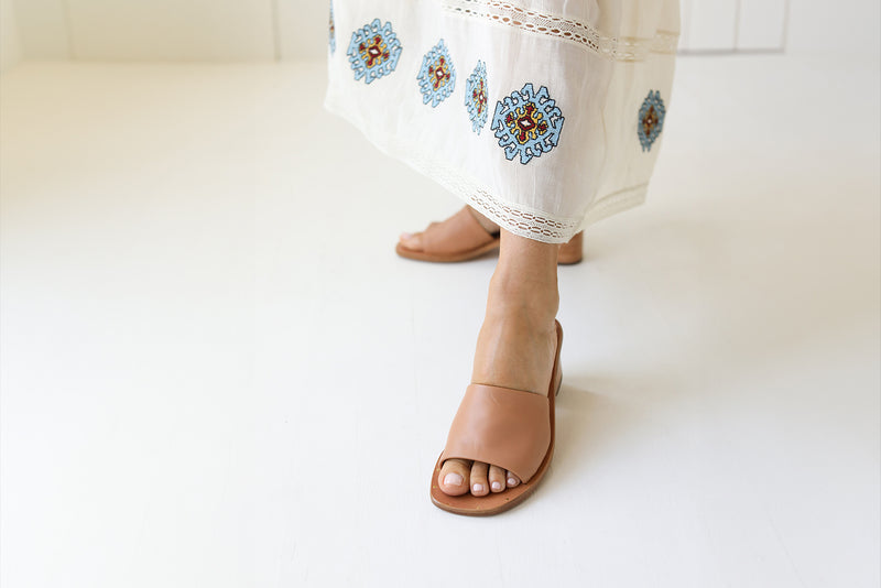 Woman wearing Emerald block heel sandal in honey with embroidered white dress