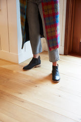 Woman wearing Falcon leather bootie in black with gray jeans and plaid coat.