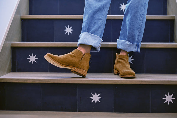 Woman wearing Falcon suede booties in chestnut with jeans on steps