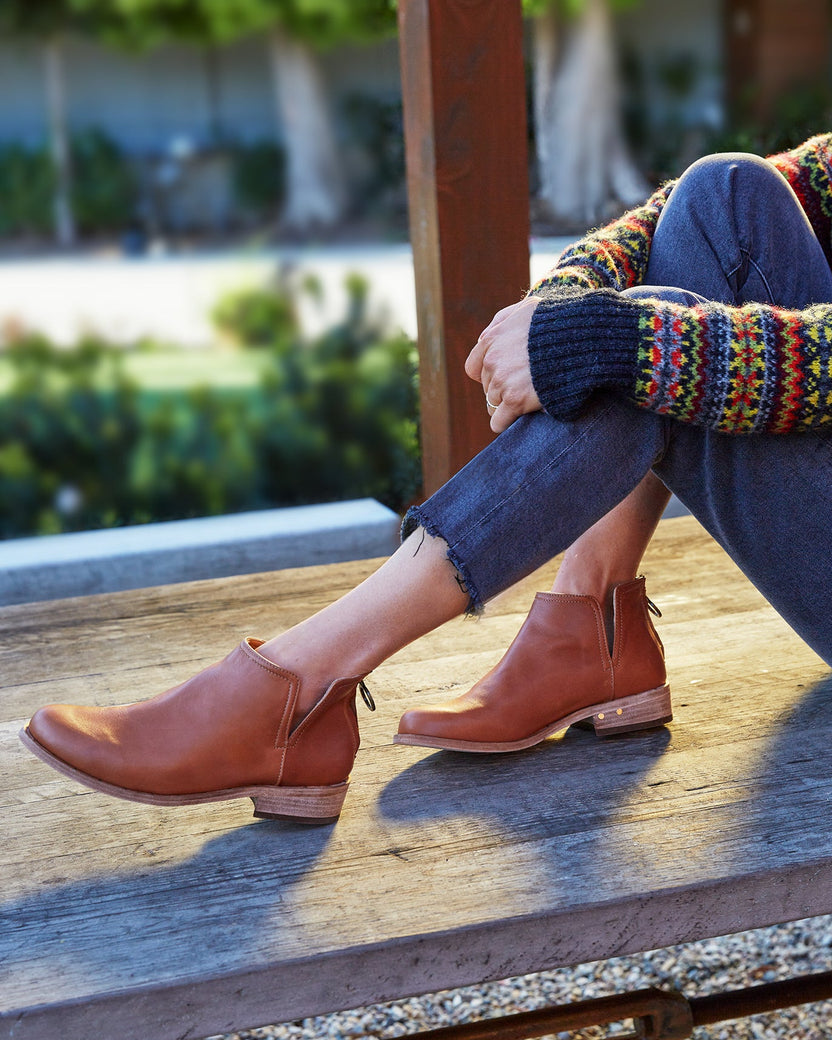 Woman wearing Falcon leather booties in cognac with jeans and sweater.