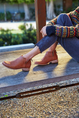 Woman wearing Falcon leather booties in cognac with jeans and sweater.