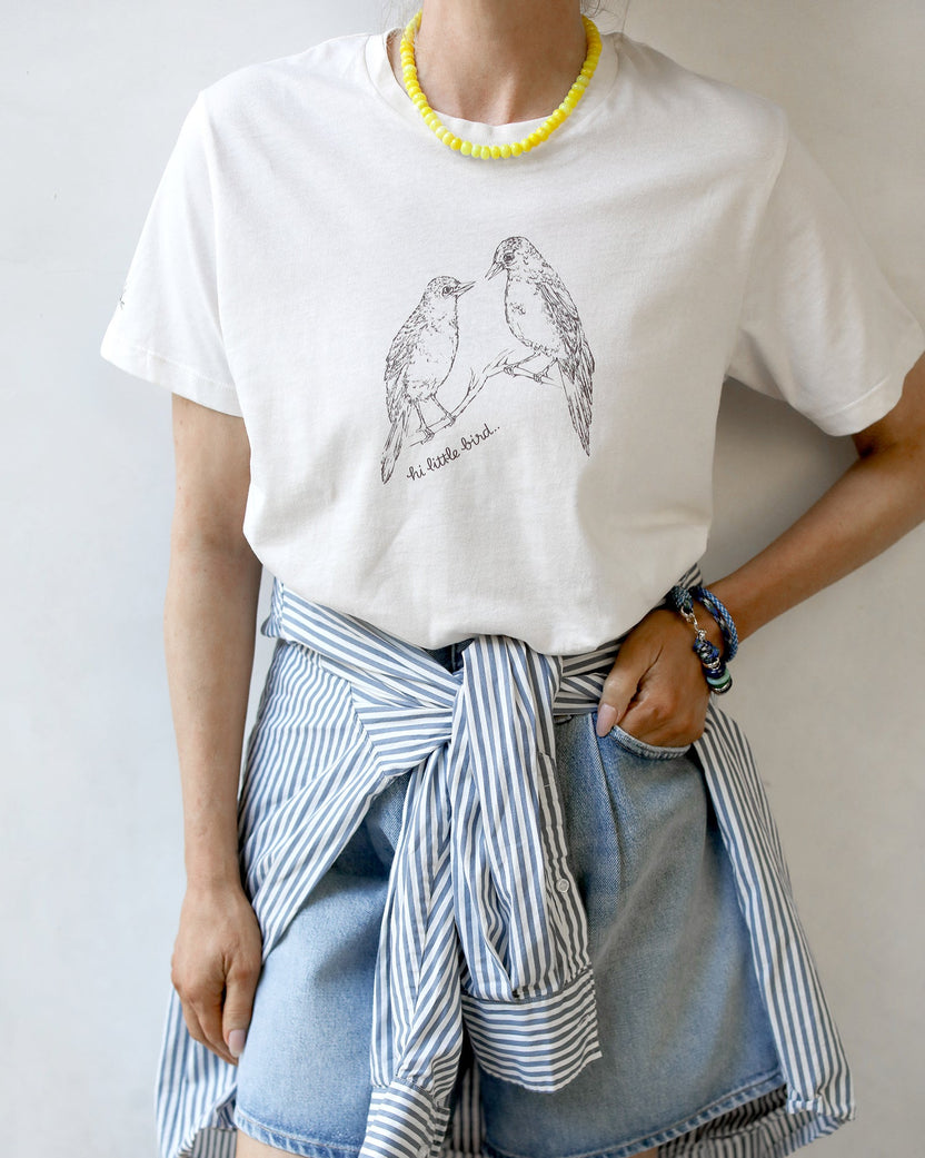 Woman wearing Feather tee shirt in vintage white with jean shorts