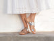 Woman wearing Finch leather toe-ring sandal in high shine silver with white eyelet dress