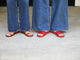 Women wearing Finch leather toe ring sandals in tan and Honeybird leather slide sandals in red with jeans