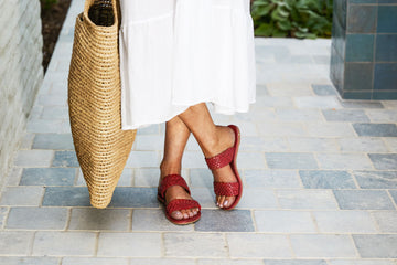 Woman wearing Flicker woven leather sandals in red with white dress and woven tote.