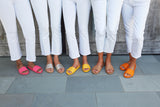 Group shot of women wearing Gallito slide sandals in azalea, platinum/beach, sunflower, honey, and tangelo.