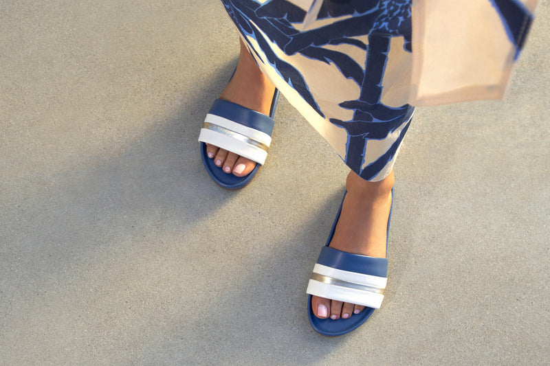 Woman wearing Gallito Stripe leather slide sandal in navy with tropical dress