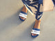 Woman wearing Gallito Stripe leather slide sandal in navy with tropical dress