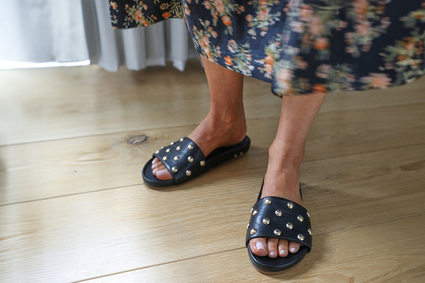 Woman wearing Gallito Stud leather slide sandal in black with floral dress