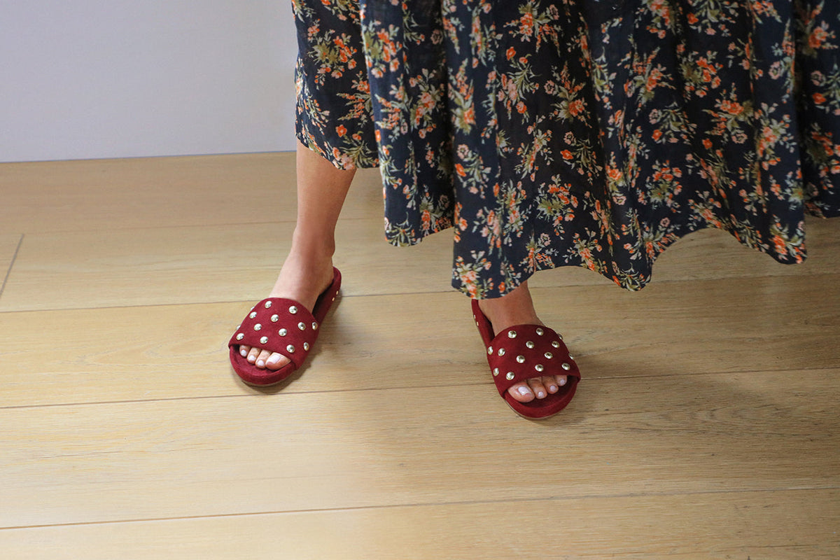 Woman wearing Gallito Stud suede sandals in port with floral dress