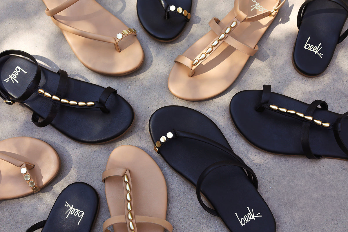 Group shot of Goldenbird leather beaded ankle-strap sandal in beach and black with Starbird leather embellished toe-ring sandal in beach and black