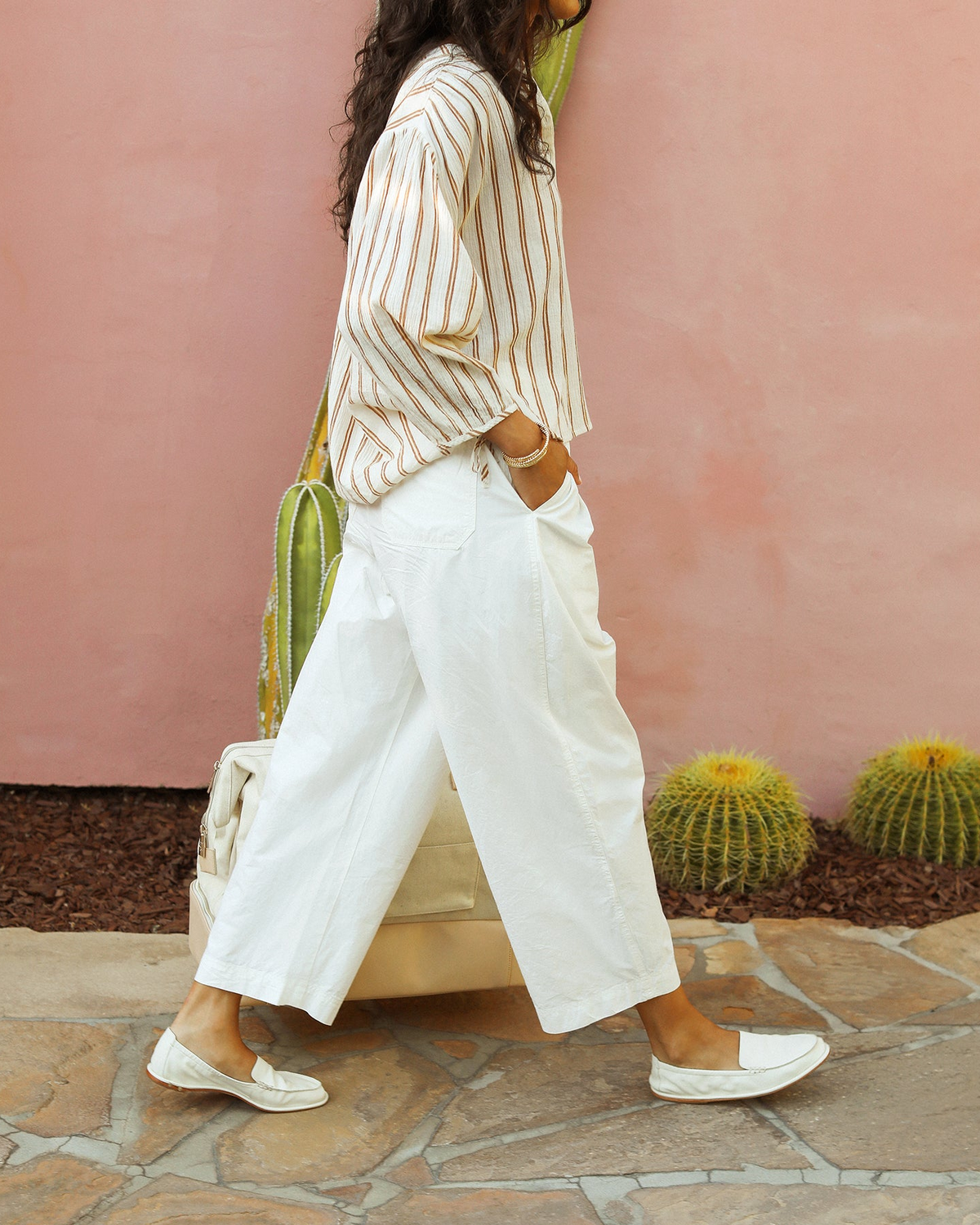 Woman wearing Griffin leather loafer in vanilla with cream pants, carrying travel bag