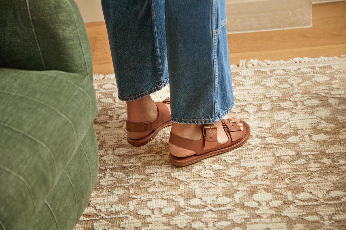 Woman wearing Huet leather buckle sandals in cognac with jeans