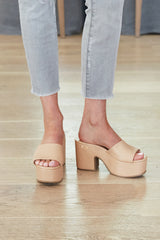 Woman wearing Ibis leather platform heel sandals in beach with light jeans