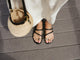 Woman wearing Itsybitsybird leather toe-ring sandals in black with dress.