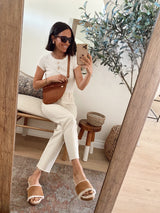 @itsybitsyindulgences wearing Gallito Mas Shearling slide in almond with white pants and top and brown fanny.