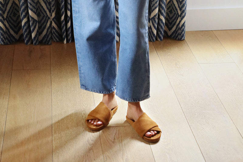 Woman wearing Kea suede slide sandals in caramel with jeans