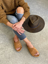 Woman wearing Kea suede slide sandals in caramel with jeans and tan sweater.
