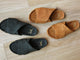 Group shot of Kea suede slide sandals in ivy and caramel on wood surface.