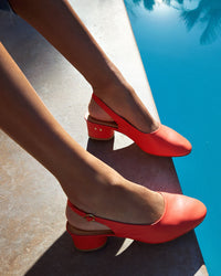 Woman wearing Lora leather heeled mules in tomato poolside