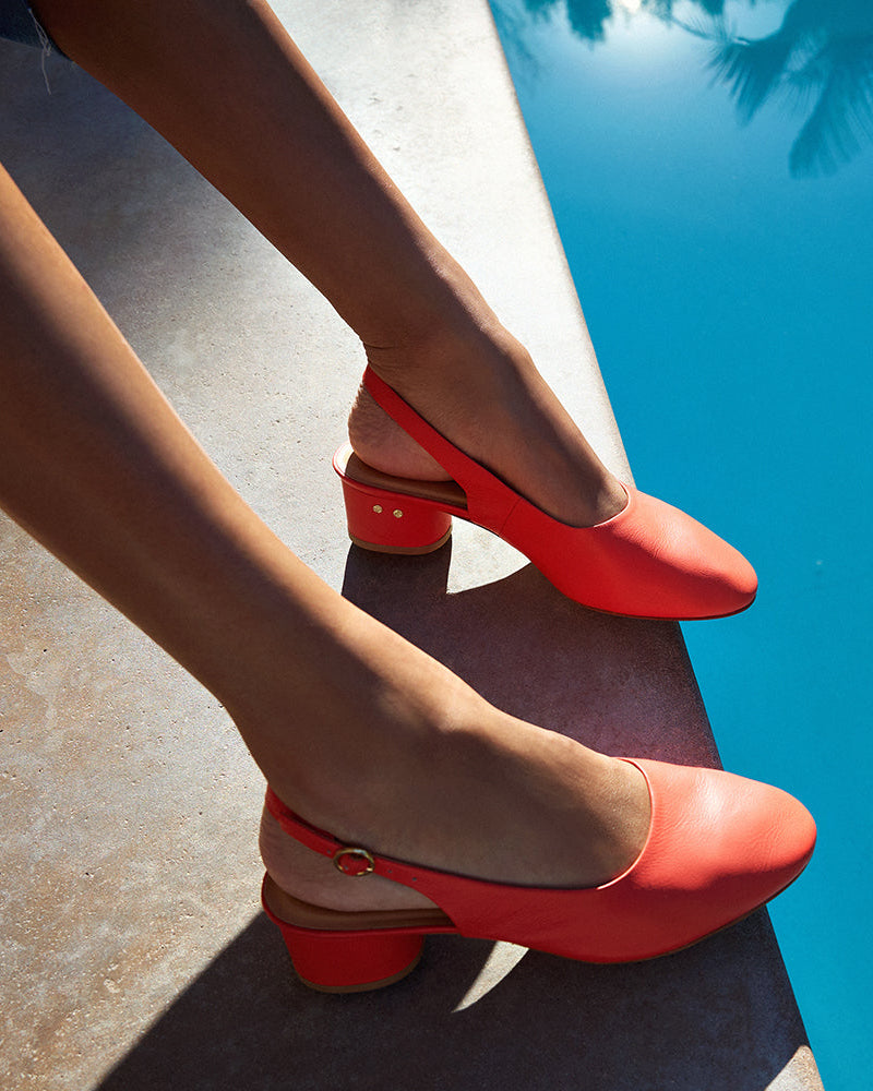 Woman wearing Lora leather heeled mules in tomato poolside