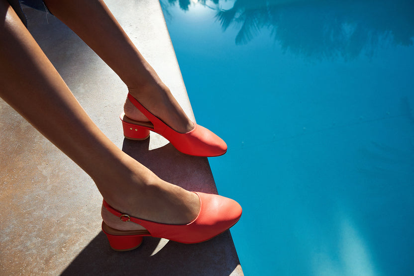Woman wearing Lora leather heeled mules in tomato poolside
