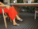 Woman wearing Lovebird leather embroidered slide sandal in black stripe with bright dress