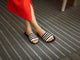 Woman wearing Lovebird leather embroidered slide sandal in black stripe with bright dress
