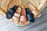 Group shot of Macaw leather strappy sandals in black and honey with Pelican platform sandals in tan, black, and honey.
