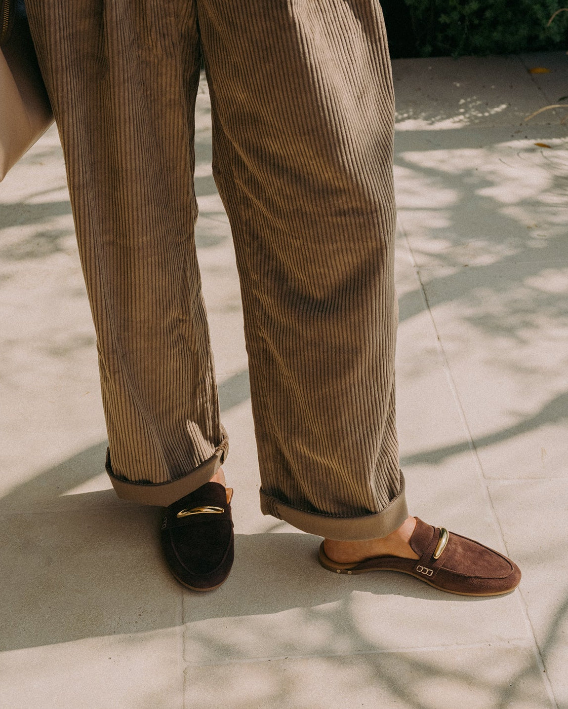 Woman wearing Mallard suede loafer in coffee with loafer charm