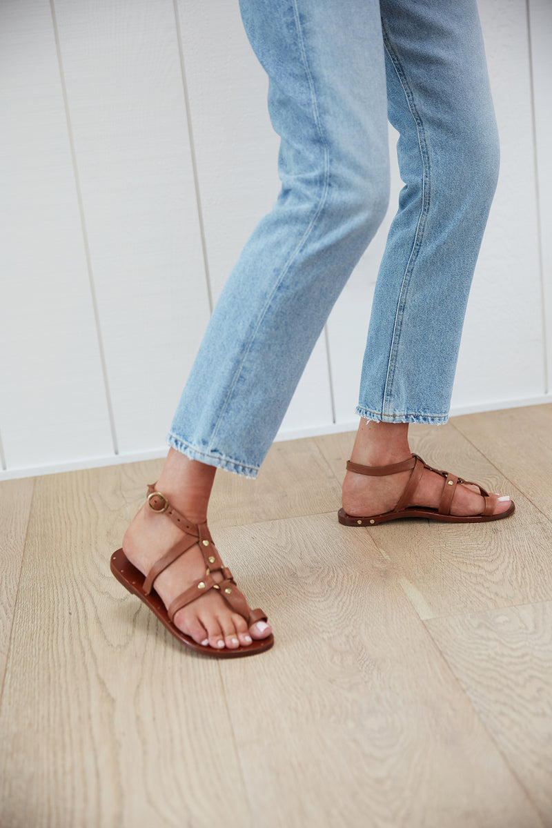 Woman wearing Miner ankle strap leather sandals in tan with jeans