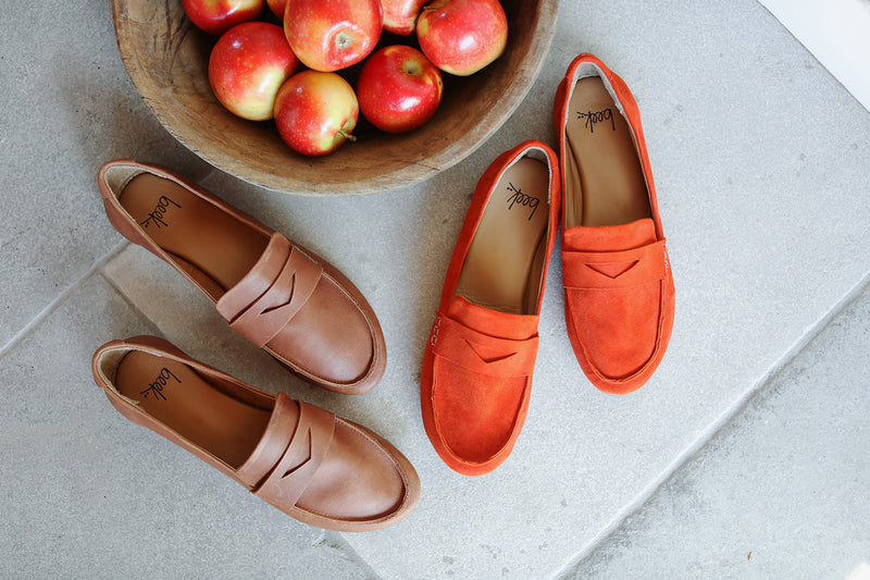 Moorhen moccasins in cognac leather and pumpkin suede next to bowl of apples.