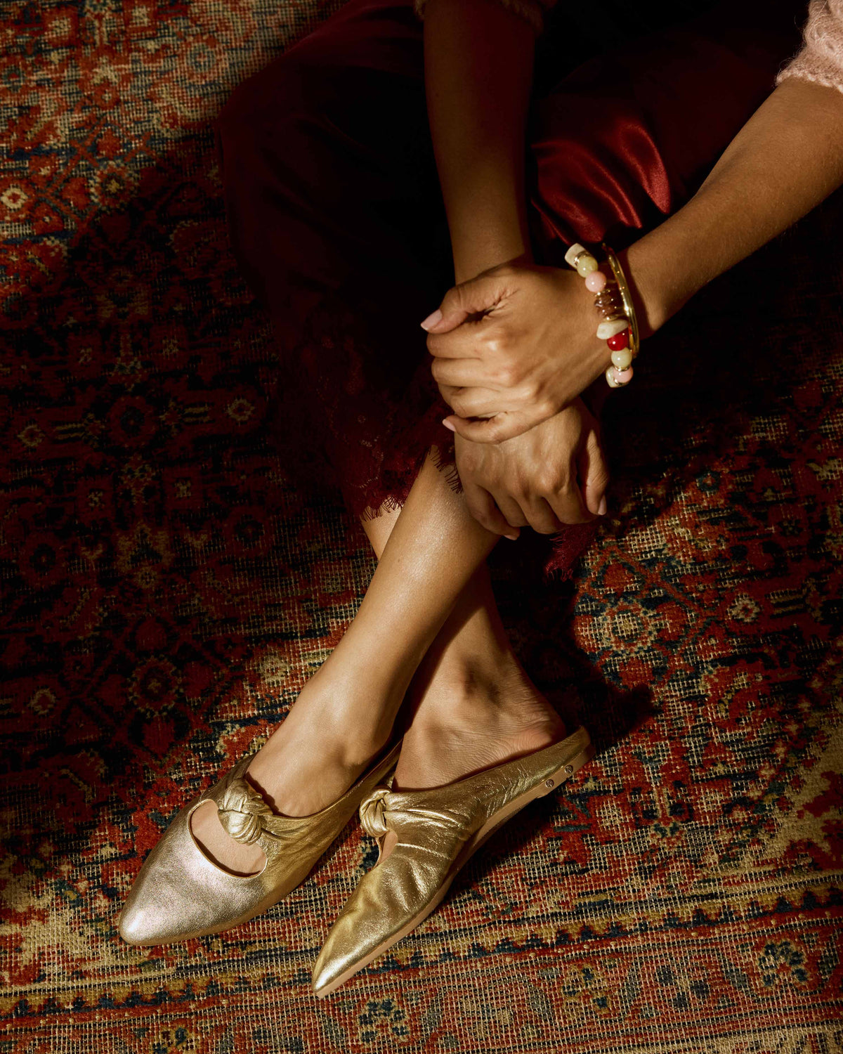 Woman wearing Noddy leather knotted mule in gold with red lace skirt
