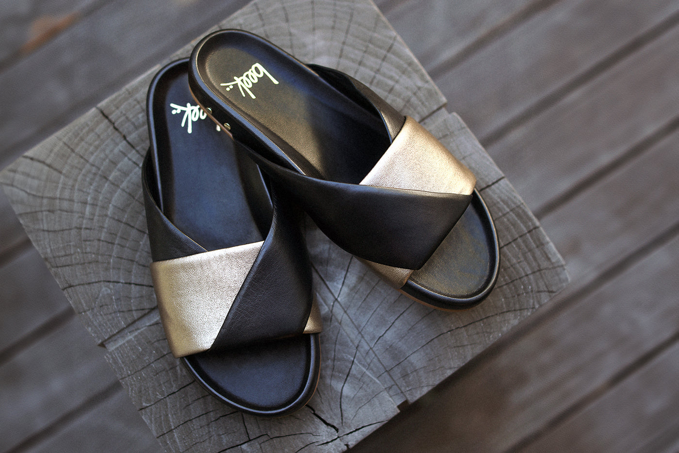 Paloma leather slide sandal in bronze/black on wooden stoop