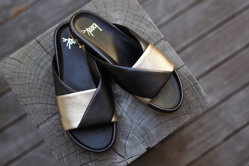 Paloma leather slide sandal in bronze/black on wooden stoop