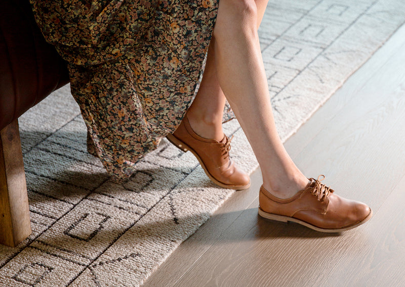 Woman wearing Partridge leather oxford shoes in cognac with floral dress.
