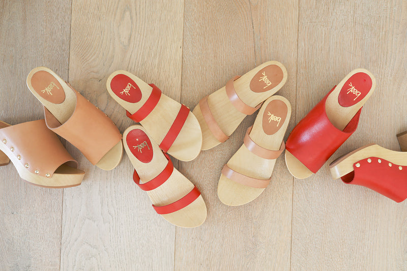 Group shot of Peacock clogs in honey and red with Dipper clogs in red and honey.