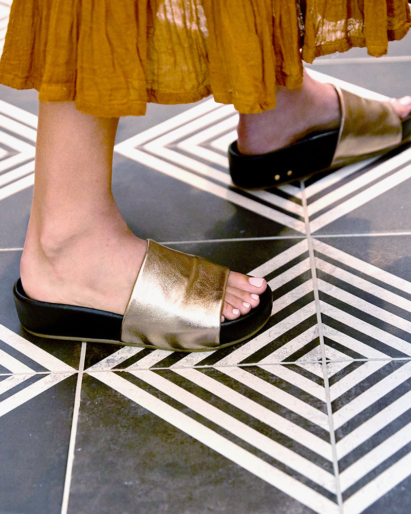 Woman wearing Pelican leather platform sandals in bronze/black with dress