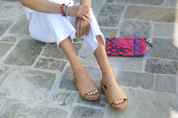 Woman wearing Pelican leather platform sandals in honey with white pants.