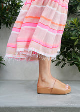 Woman wearing Pelican platform sandals in honey with pink striped dress.