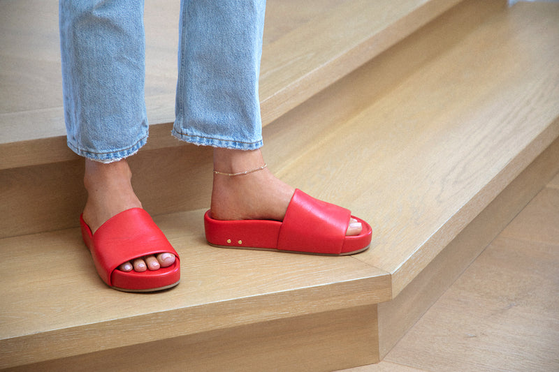 Woman wearing Pelican leather platform slide sandals in lipstick with jeans