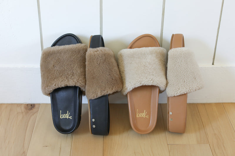 Group shot of Pelican Shearling platform slide sandals in black/bronze and natural/honey.